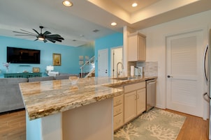 A modern kitchen with granite countertops, white cabinetry, and a built-in dishwasher.