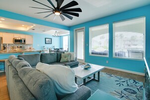 A modern living room with a gray sectional sofa, a white coffee table, and a blue patterned rug.