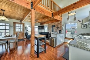 A spacious kitchen with wooden beams, a dining area with a table and chairs, and a view through a large window. - Great for Families! Fredericksburg Home w/ Hot Tub (Fredericksburg)