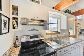 A modern kitchen with white cabinets, a stainless steel stove, and a granite countertop. - Great for Families! Fredericksburg Home w/ Hot Tub (Fredericksburg)