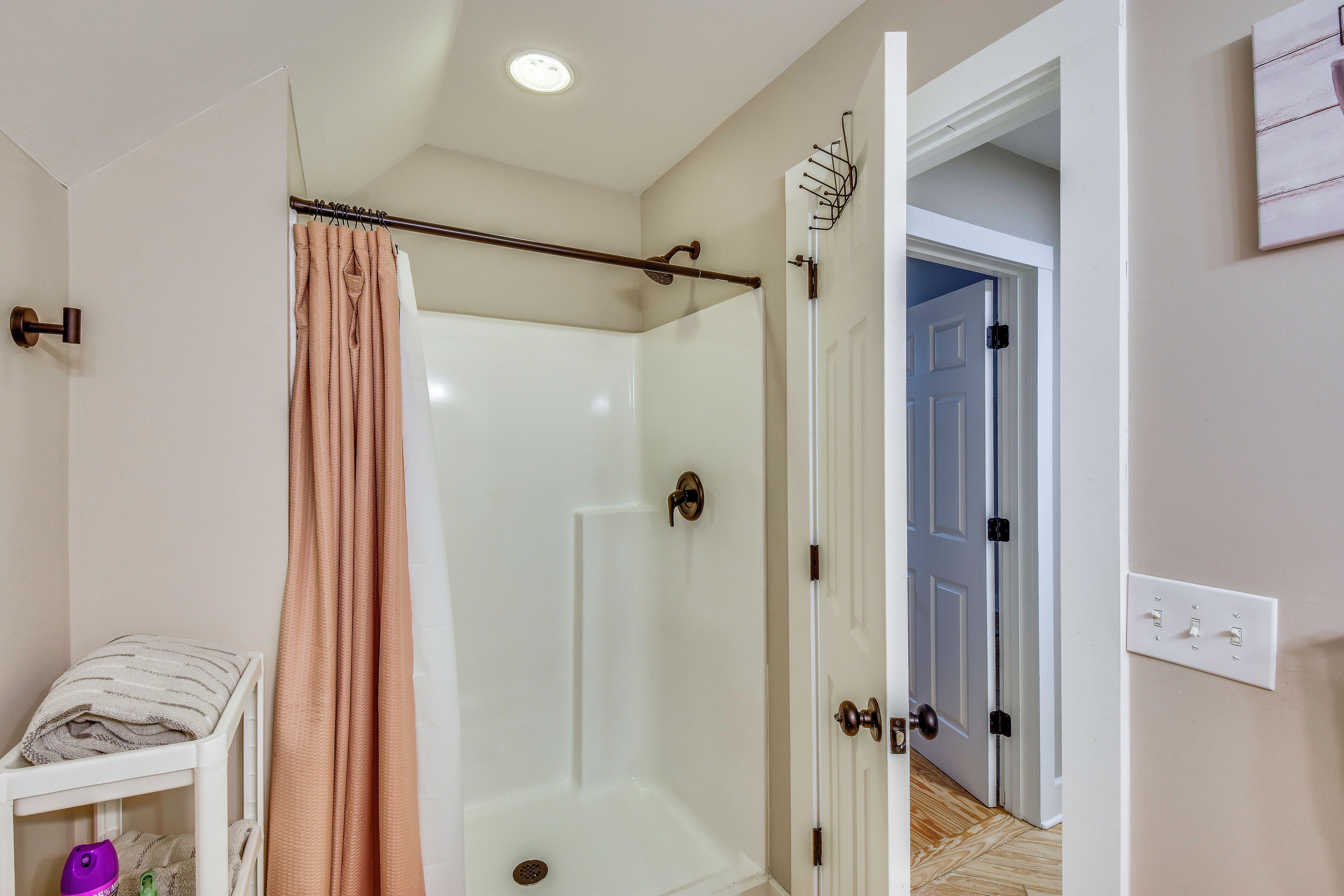 A shower with a glass door, a towel rack, and a baby changing station.