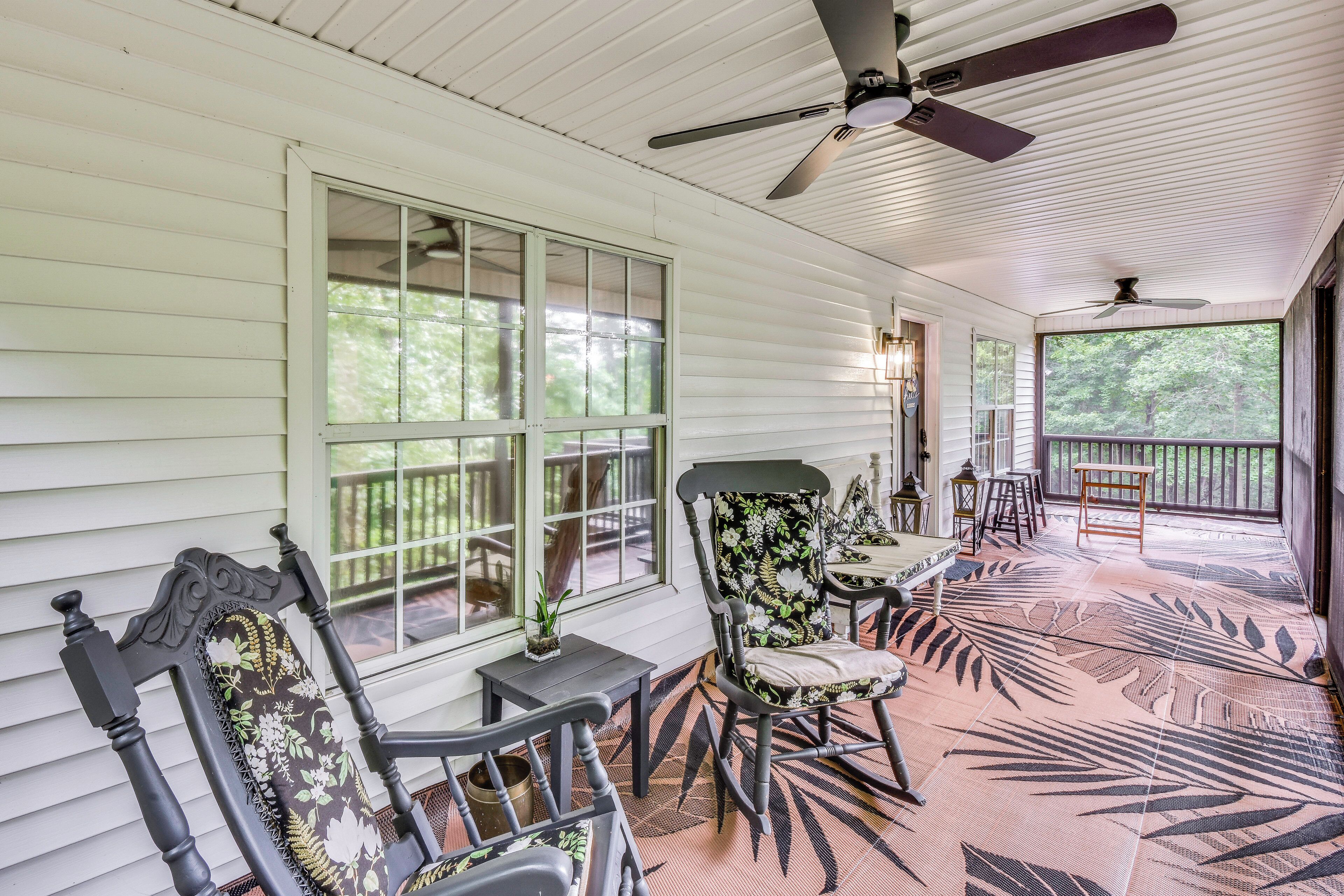 A covered porch with a ceiling fan, a table, chairs, and a view of the outdoors.