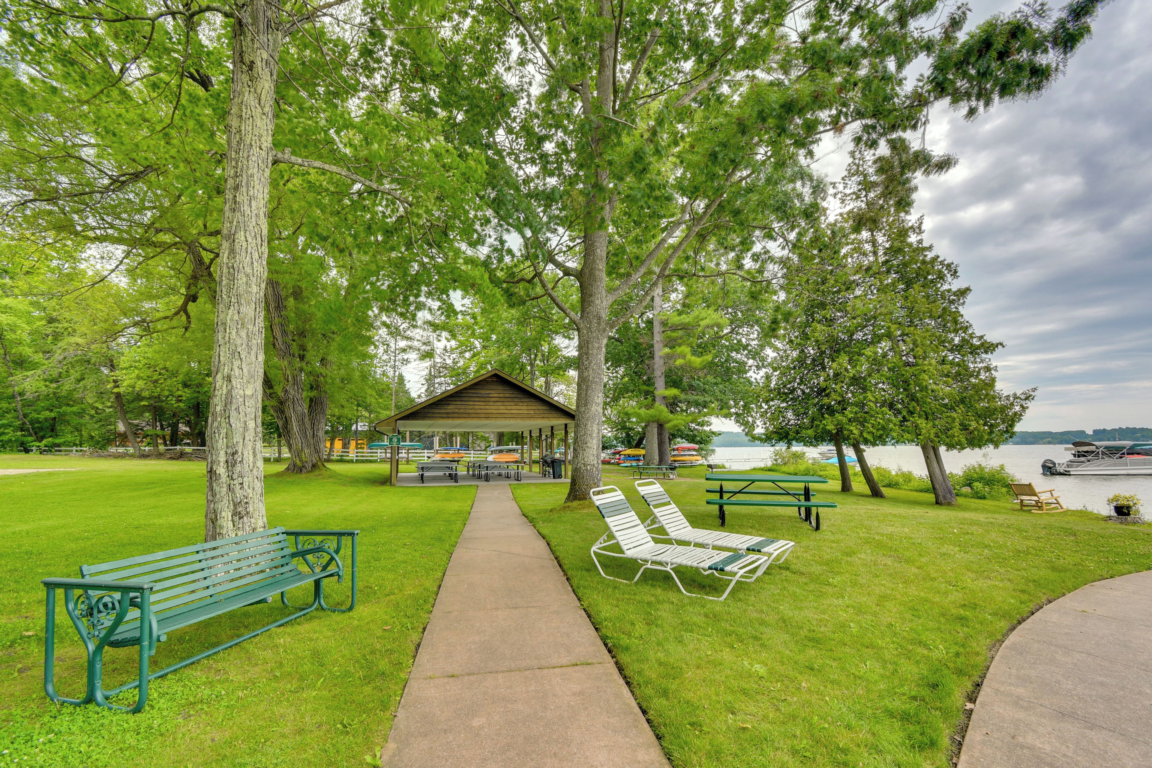 A park with a covered picnic area, benches, and a view of a lake.