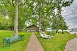 A park with a covered picnic area, benches, and a view of a lake.