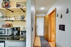 A compact kitchen with a microwave, coffee maker, and storage shelves.