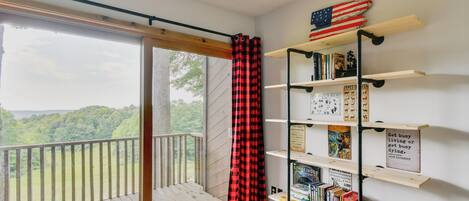 Ein Zimmer mit Balkon, Bücherregal und Blick ins Freie.