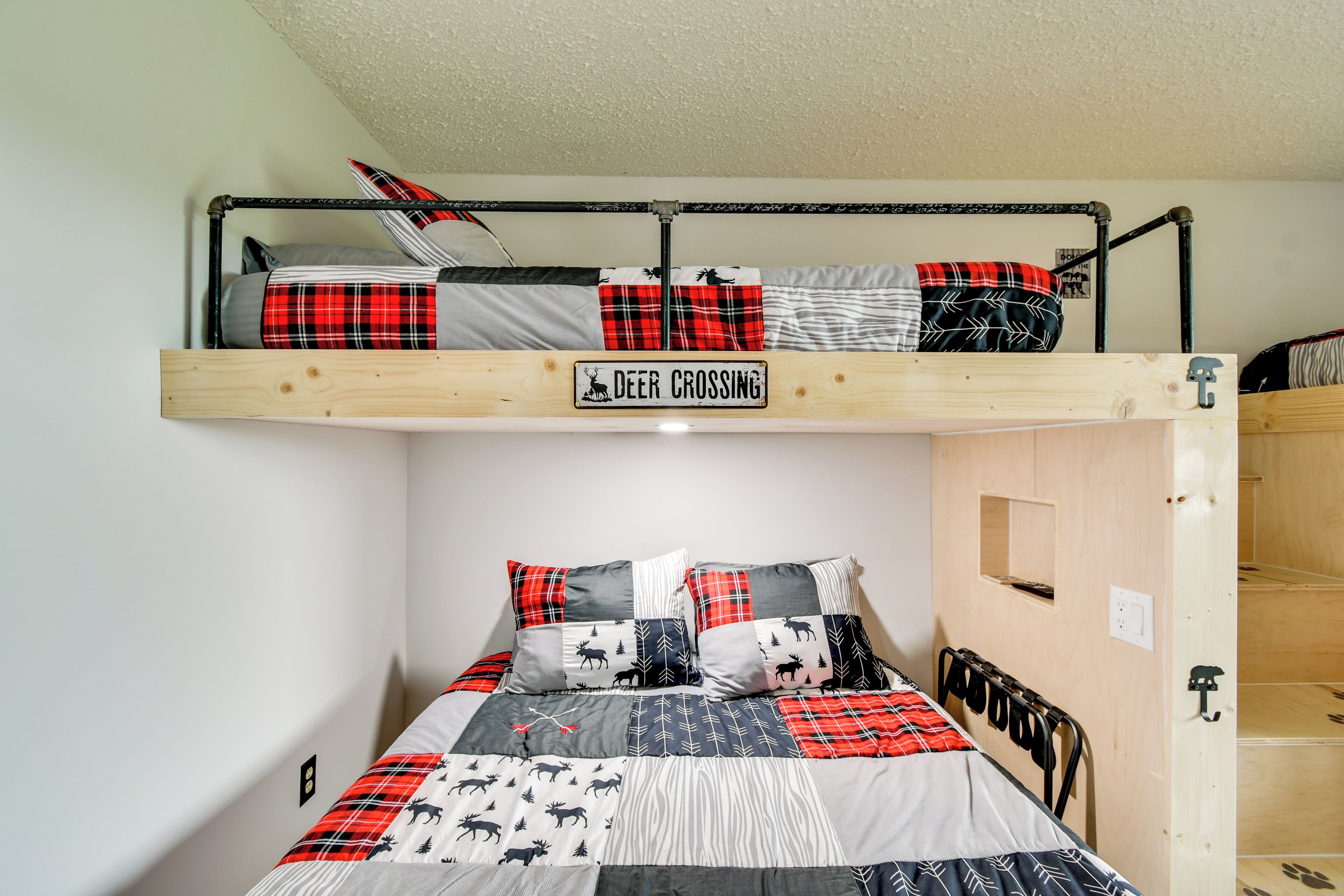 A bunk bed with a 'Deer Crossing' sign, a patchwork quilt, and a metal headboard.
