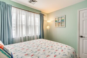 Une chambre à coucher avec un lit, des rideaux, une lampe fixée au mur et un tableau.