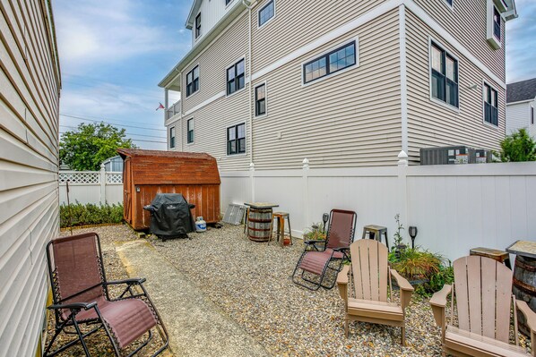 A backyard with outdoor seating, a barbecue grill, and a shed.