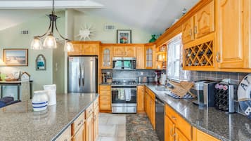 A spacious kitchen with wooden cabinets, stainless steel appliances, and a granite countertop.