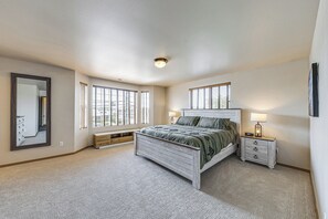 Un dormitorio con cama, mesitas de noche, un espejo y ventanas.