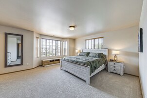 Un dormitorio con cama, mesitas de noche, un espejo y ventanas.