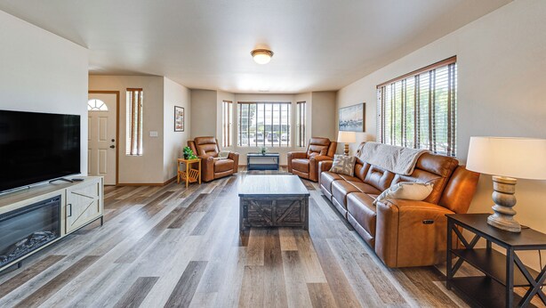 A spacious living room with a flat-screen TV, leather sofas, a coffee table, and large windows. - Walk to Town! Charming La Conner Home (La Conner)