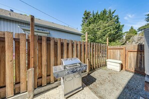 Ein Garten mit Grill, Holzpforte und einem Haus.