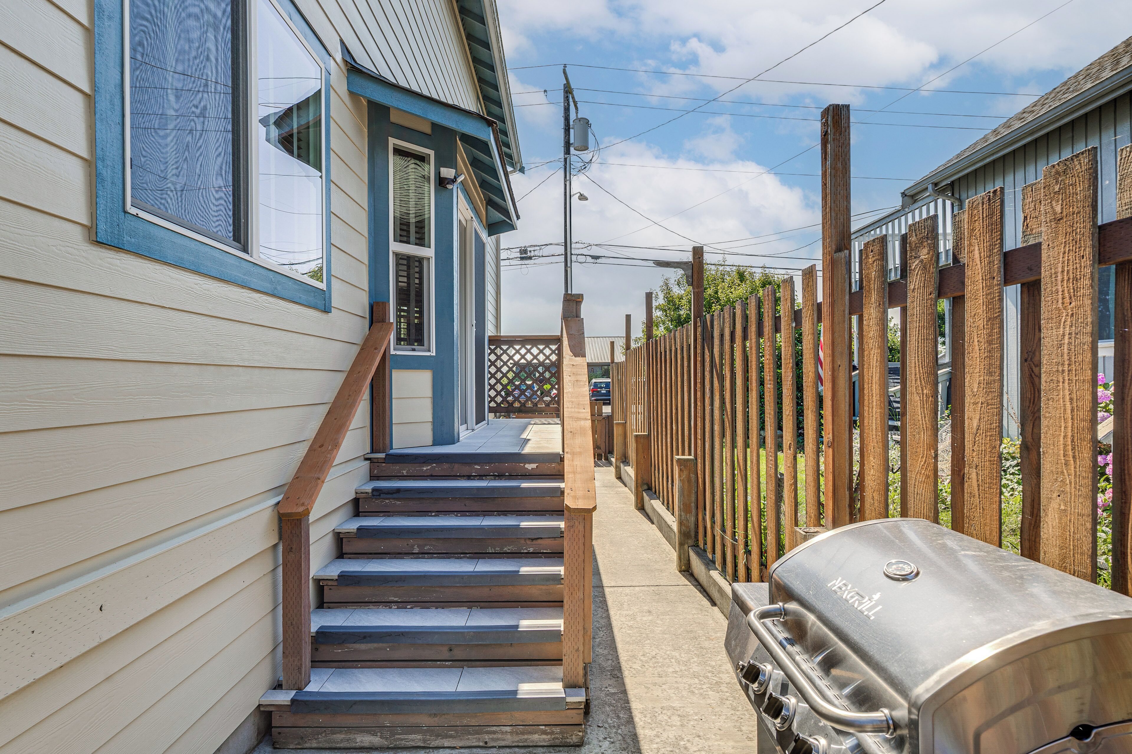 Eine Holztreppe führt zu einem Haus mit Grill im Freien.
