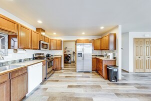 Una cocina con armarios de madera, electrodomésticos de acero inoxidable y piso con diseño.