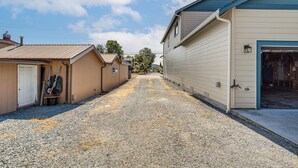 A narrow gravel driveway leading to a row of single-story buildings with attached garages. - Walk to Town! Charming La Conner Home (La Conner)