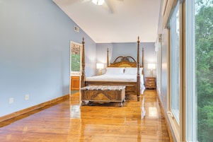 Un dormitorio con cama con dosel, un banco de madera y un ventanal grande.