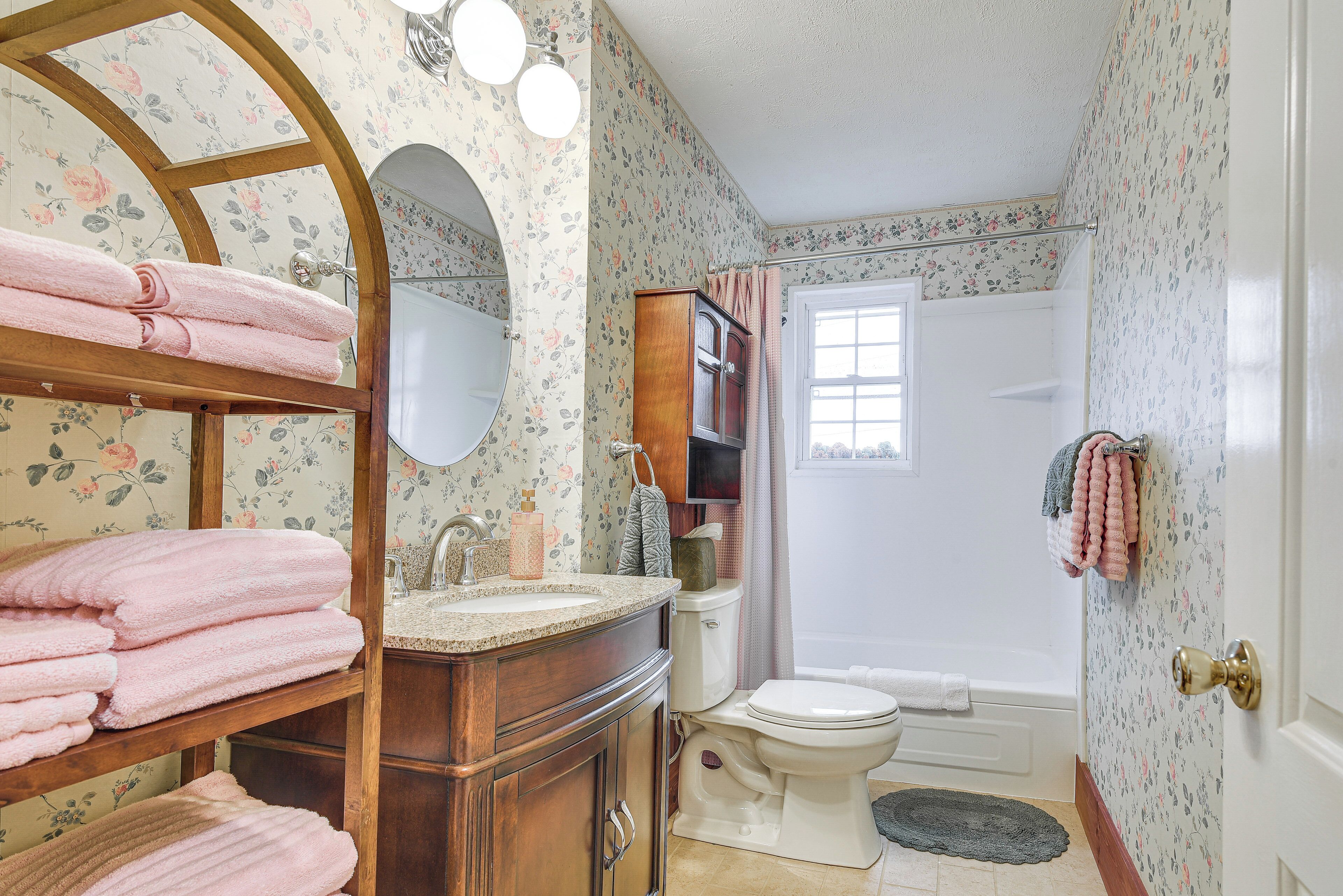 A bathroom with a wooden vanity, a toilet, a bathtub, and a window.