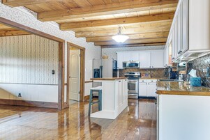 Una cocina con vigas de madera, armarios blancos y un horno de acero inoxidable.