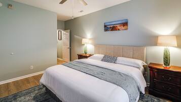 A hotel room with a bed, bedside lamps, a painting, and a ceiling fan.