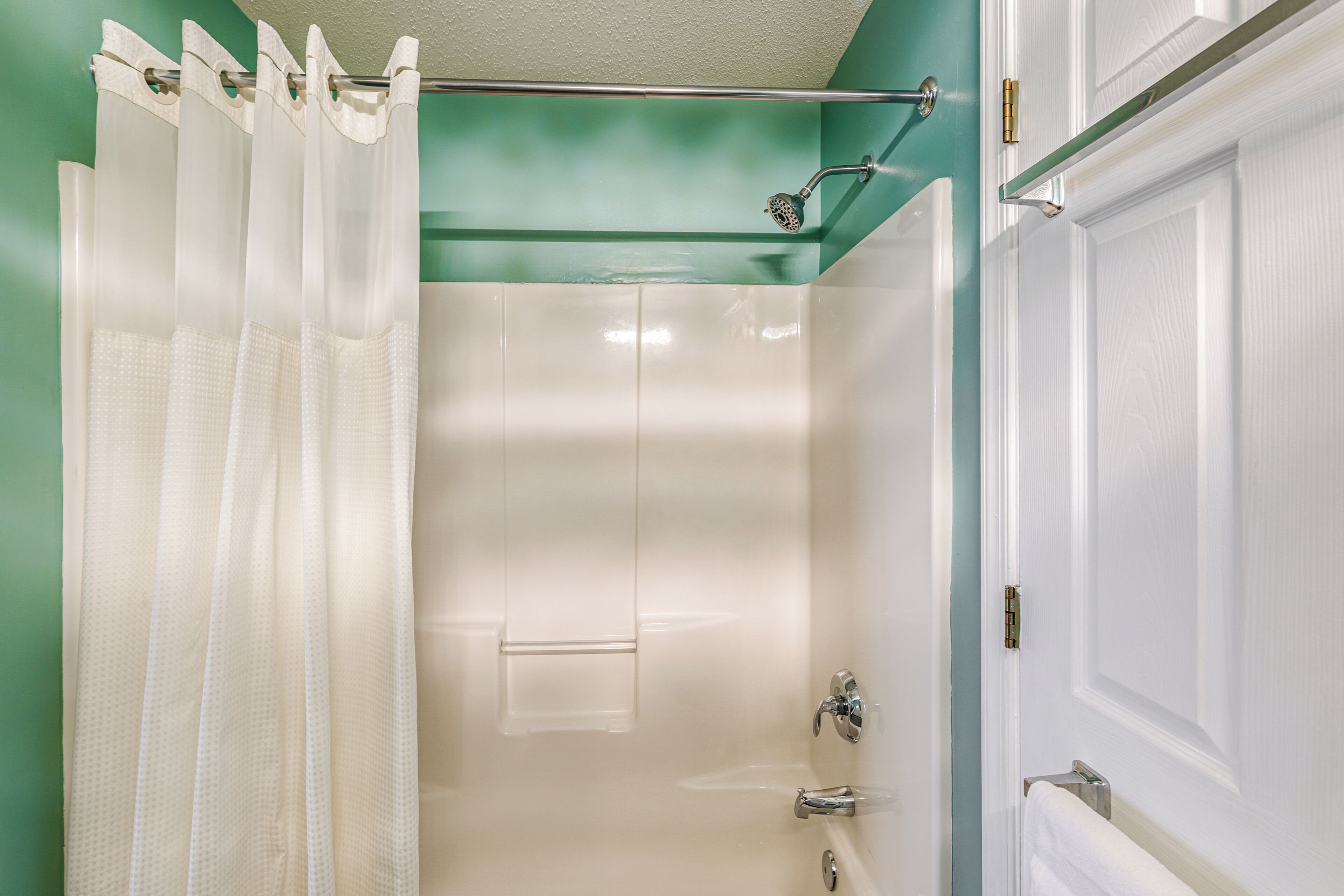 Un baño con ducha, puerta de vidrio y barra para toallas.