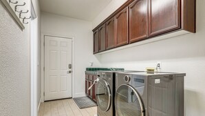 A laundry room with a door, wooden cabinets, and a washing machine.