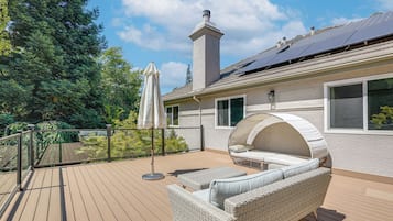 A deck with outdoor furniture, a covered seating area, and a chimney.