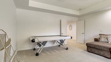 A room with a pool table, a couch, and a door.