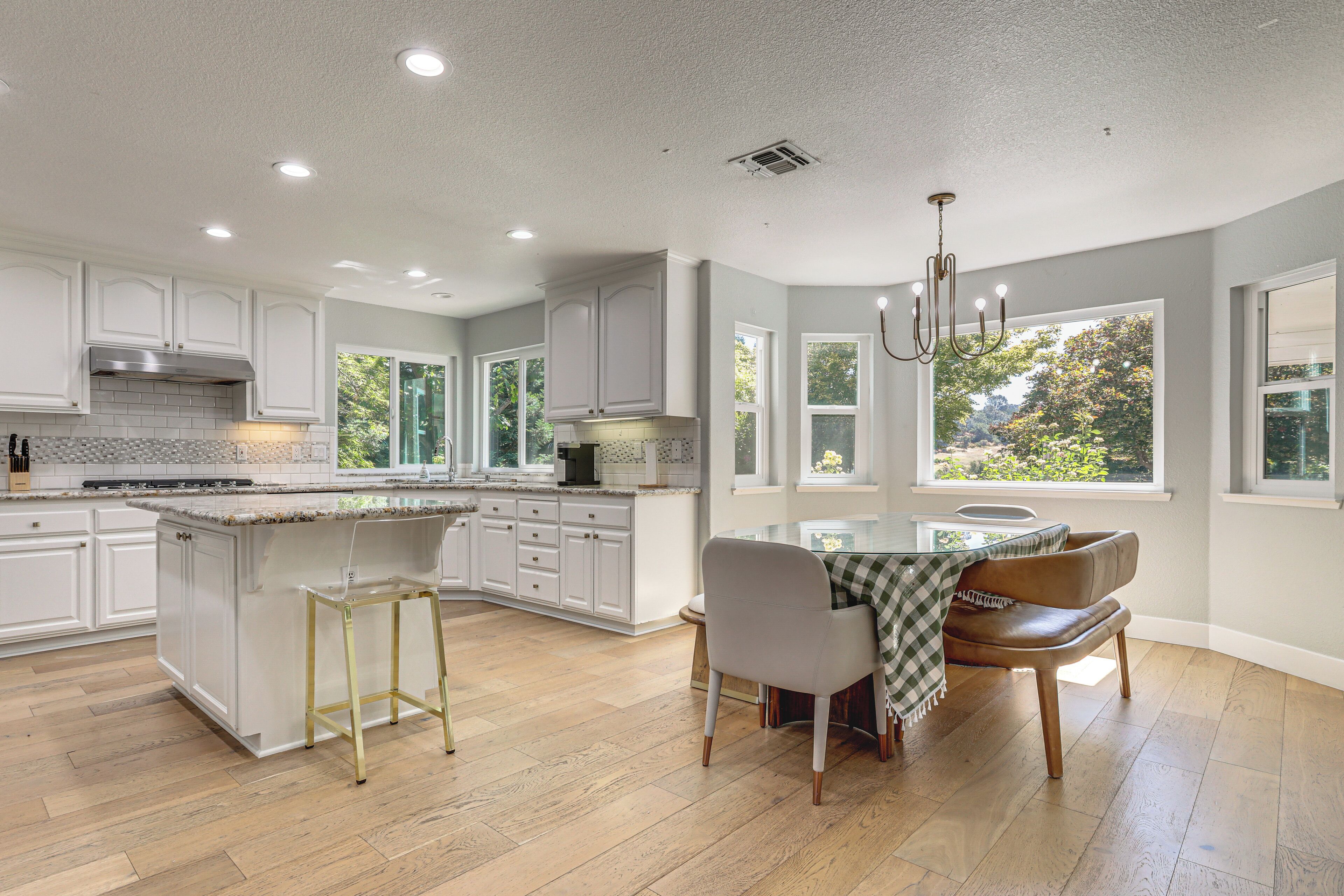 A spacious kitchen with a large island, white cabinetry, and a dining area with a table and chairs.