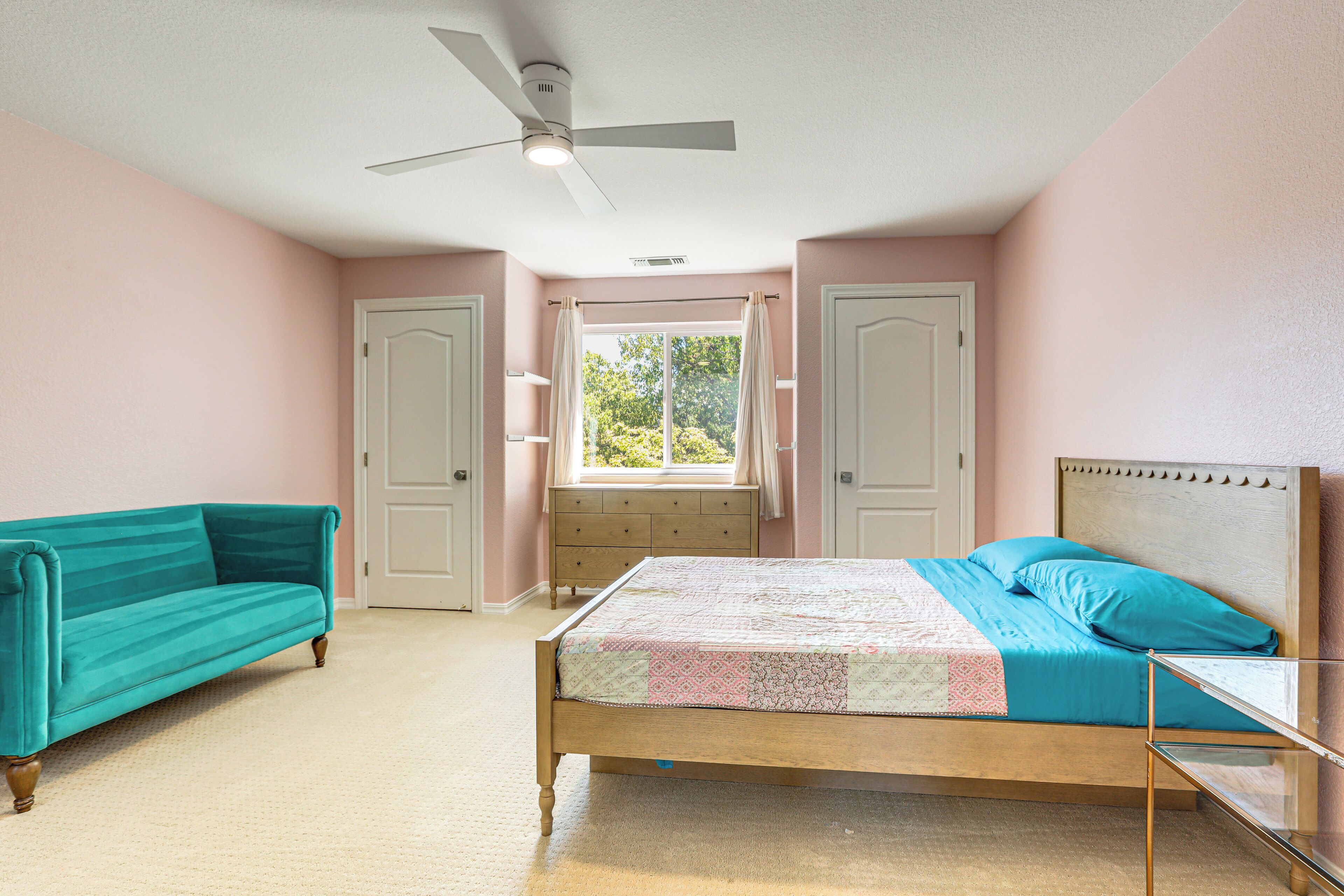 Une chambre à coucher avec un lit, une fenêtre, un ventilateur de plafond et un canapé de couleur turquoise.