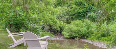 A wooden chair and table set up by a stream in a lush green area.