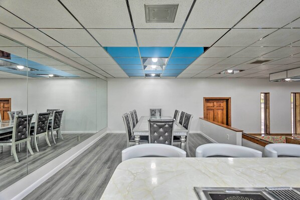 A conference room with a marble table, upholstered chairs, a glass partition, and a wooden door.