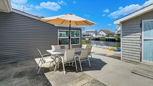 A patio with a table and chairs, a large umbrella, and a view of a body of water with boats.