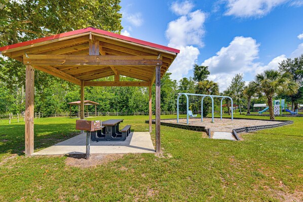 A park with a wooden pavilion, picnic tables, and playground equipment.