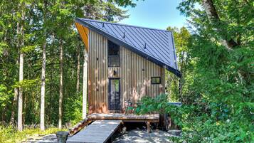 A cabin with a sloped roof, a front porch, and a small deck.