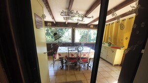 A dining area with a table and chairs, a window with a view of trees, and a kitchen area with a sink and cabinets. - The Symphony of the Birds (Villelongue-d'Aude)