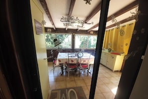 Ein Essbereich mit Tisch und Stühlen, ein Fenster mit Blick auf Bäume und eine Küchenzeile mit Spüle und Schränken.