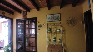 A room with a wooden ceiling, a door with glass panels, a metal shelf with kitchenware, and a wall-mounted picture. - The Symphony of the Birds (Villelongue-d'Aude)