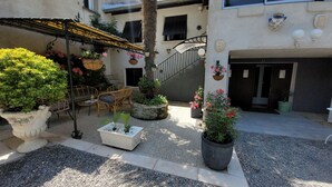 A courtyard with outdoor seating, potted plants, and a staircase leading to an upper level. - The Symphony of the Birds (Villelongue-d'Aude)