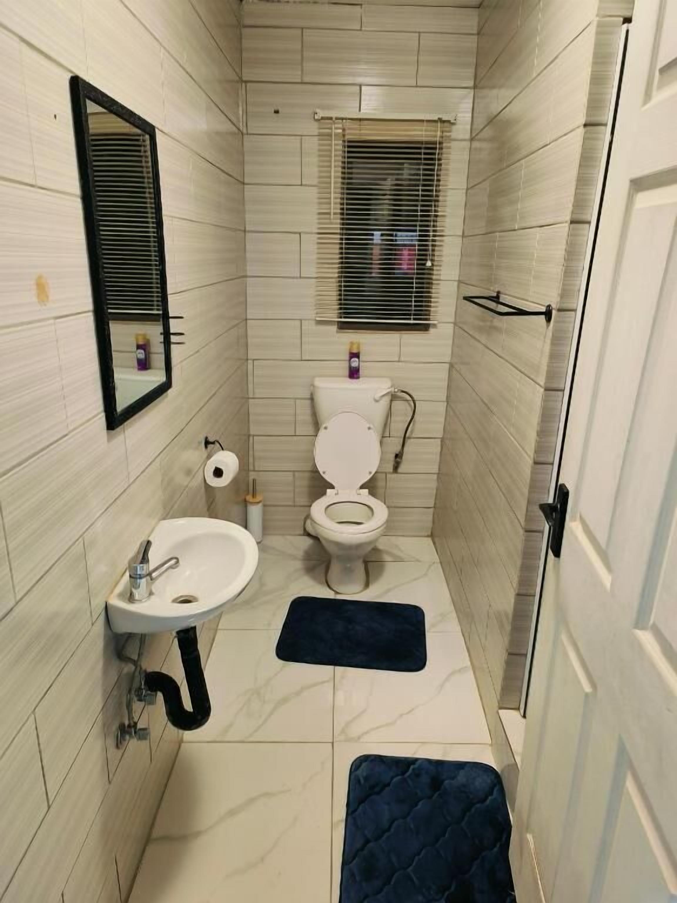 Un baño pequeño con inodoro, lavamanos y espejo.