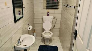 Un baño pequeño con inodoro, lavamanos y espejo.