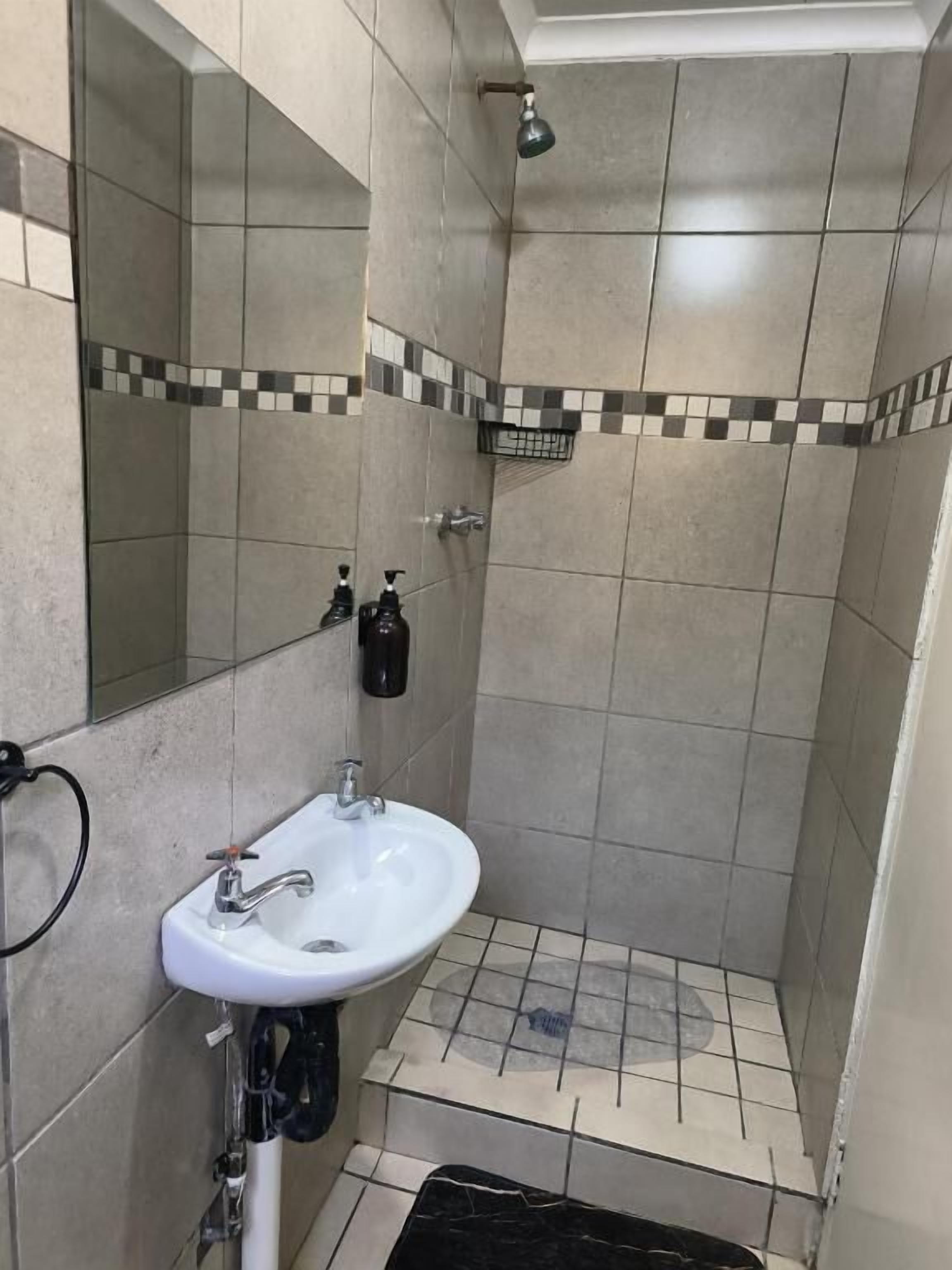 Ein Badezimmer mit weißem Waschbecken, einem Spiegel und einer Duschkabine.