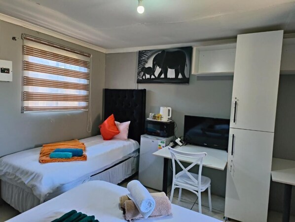 A room with two beds, a desk, a television, and a cabinet.