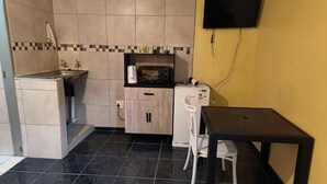 A compact kitchen with a sink, microwave, and a small table with a chair. - Room-acama Guest House 455 Long rd, Welk (Matjhabeng)