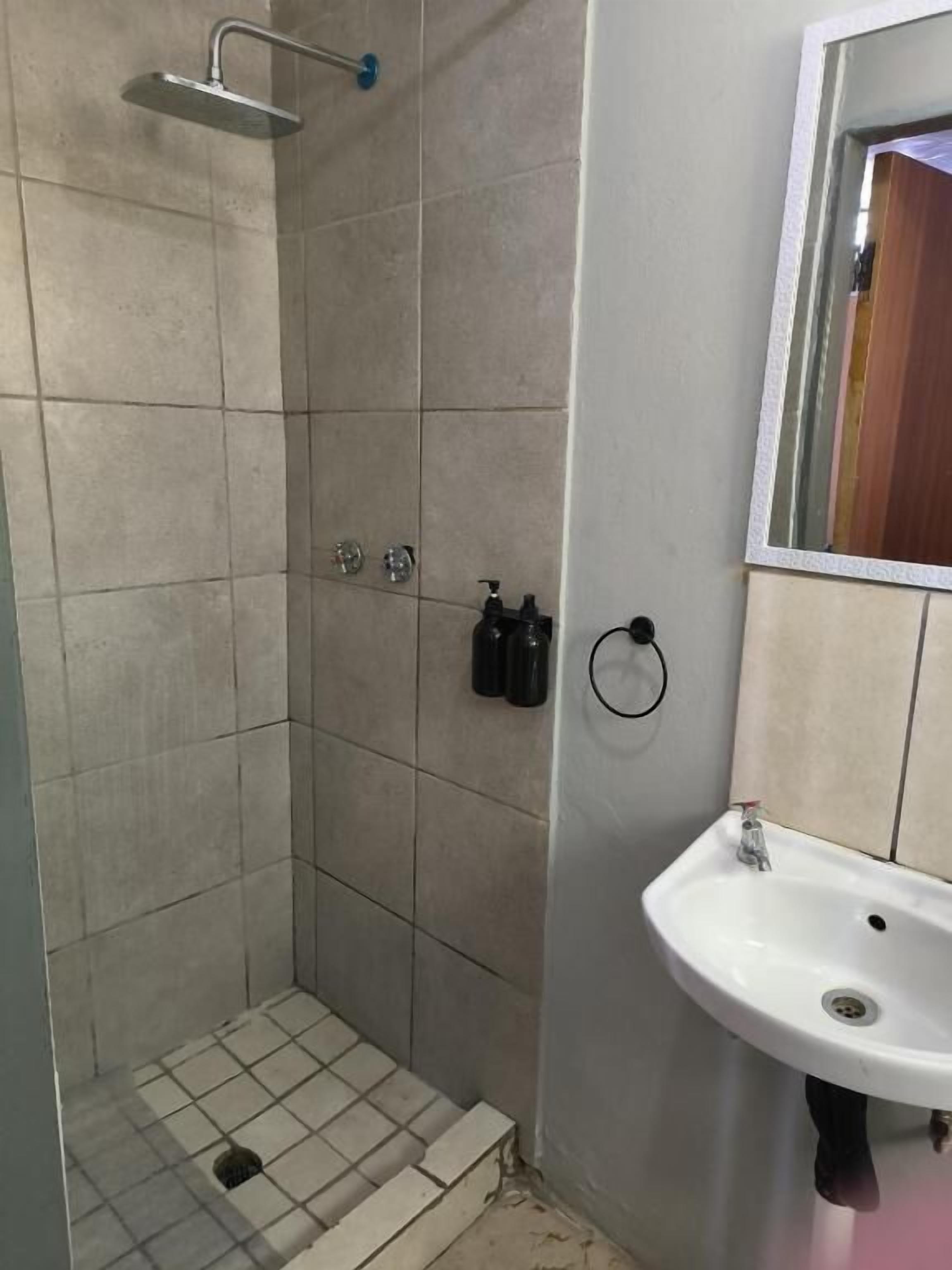 A bathroom with a shower, sink, and mirror.