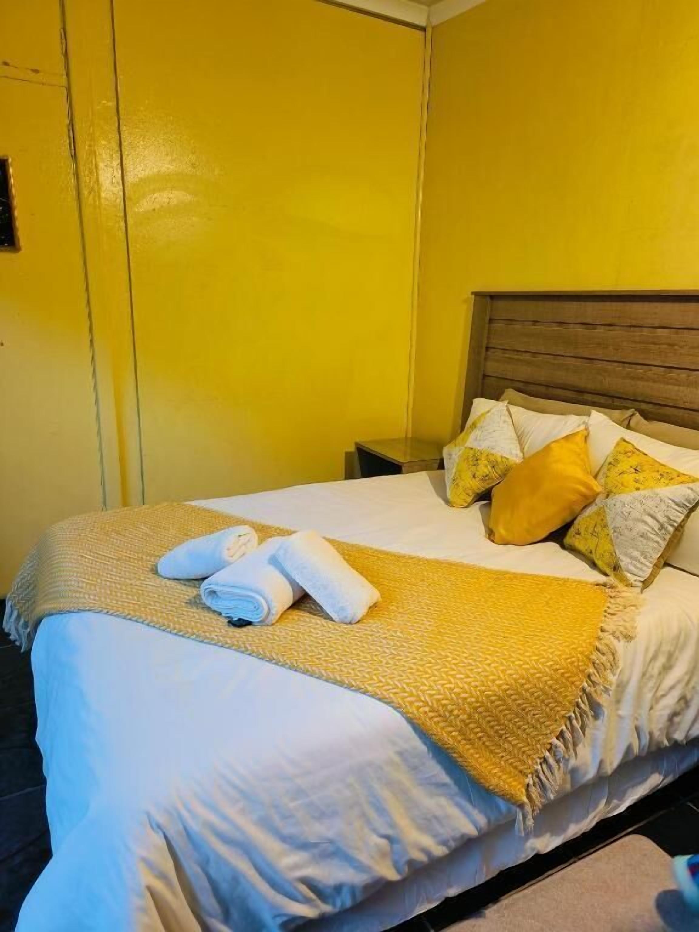 A hotel room with a bed, pillows, a blanket, and a folded towel.
