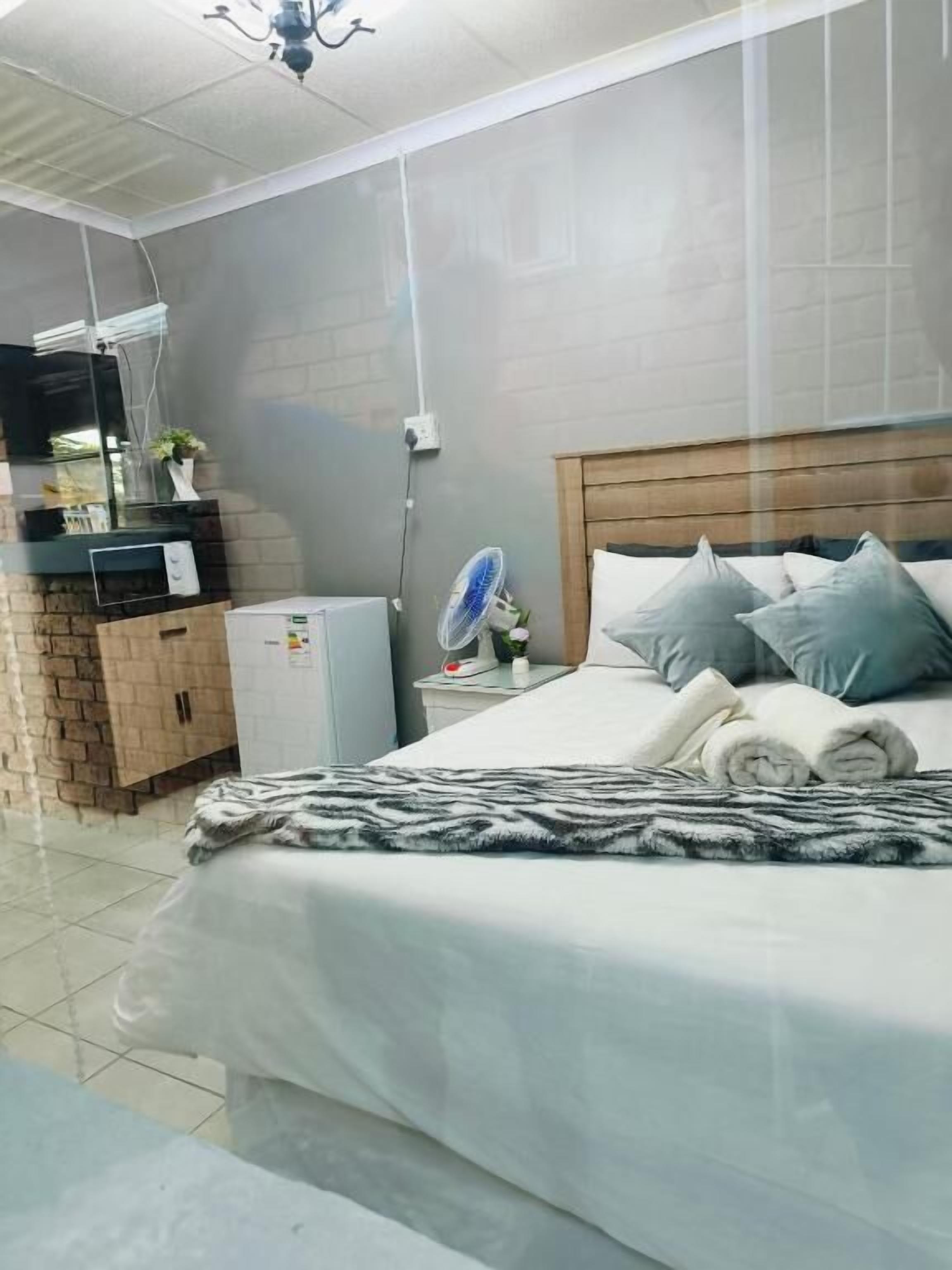 A bedroom with a bed, a bedside table, a fan, and a small heater.