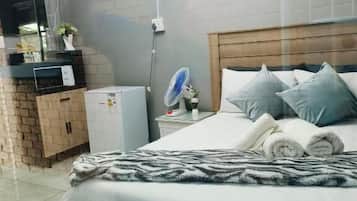 A bedroom with a bed, a bedside table, a fan, and a small heater.