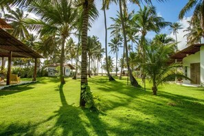 A lush garden with palm trees and a clear sky. - Pousada Vila do Patacho (Porto de Pedras)